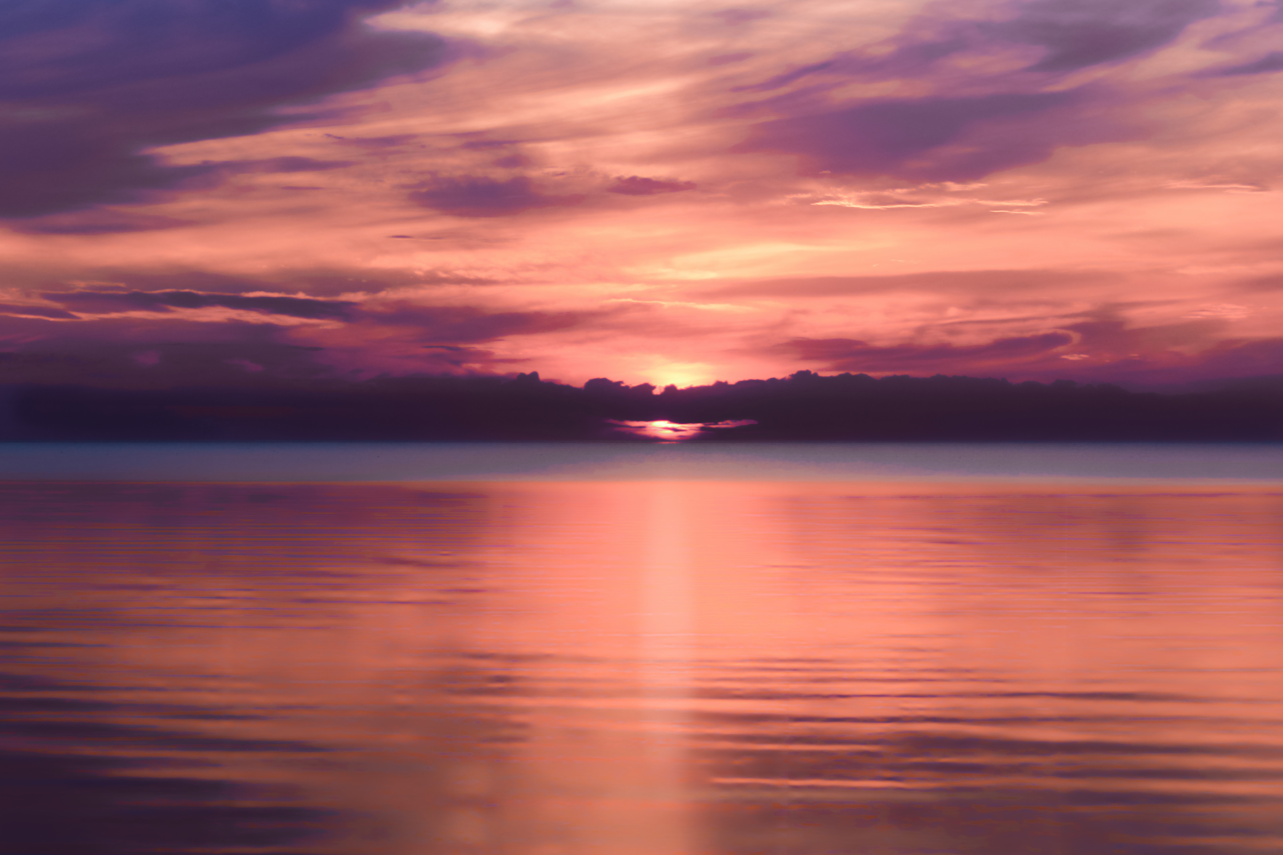 Purple and orange sunset over calm water with soft clouds.