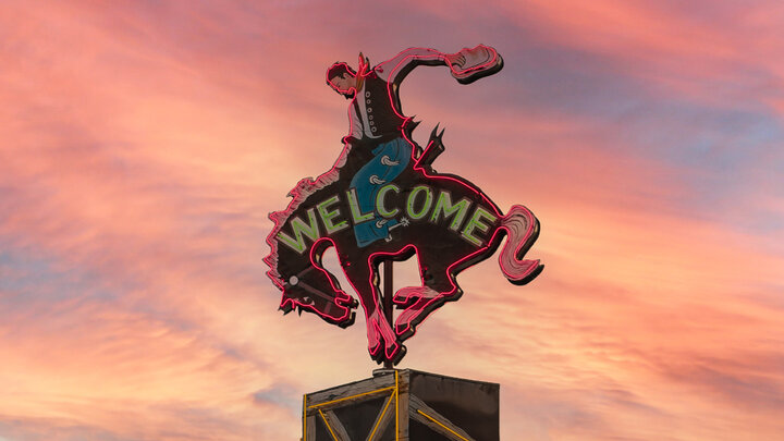 A neon sign of a cowboy riding a bucking bronco